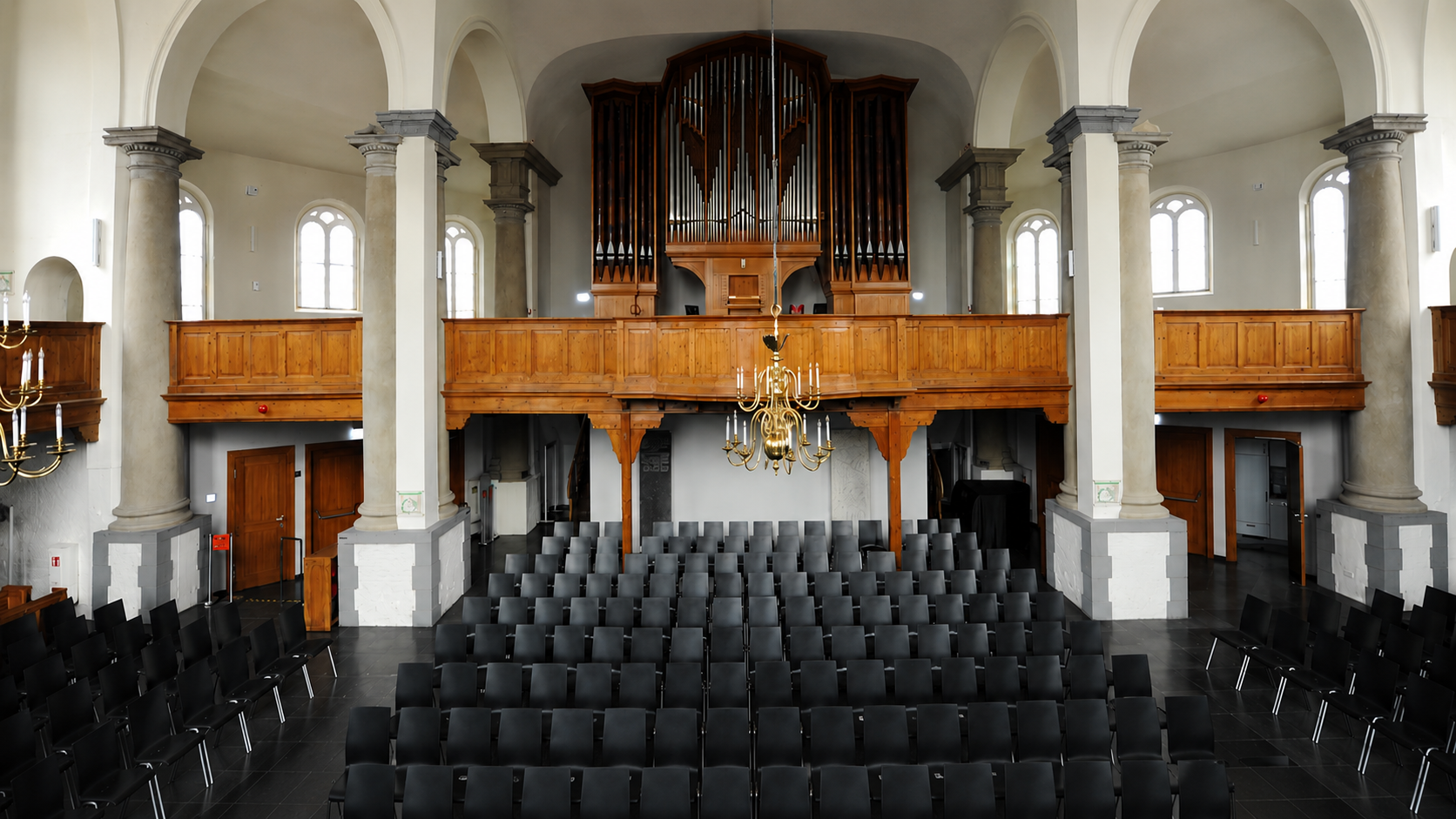 Der Kirchenraum der Neuen Kirche mit großer Orgel, Holzempore und Reihen schwarzer Stühle